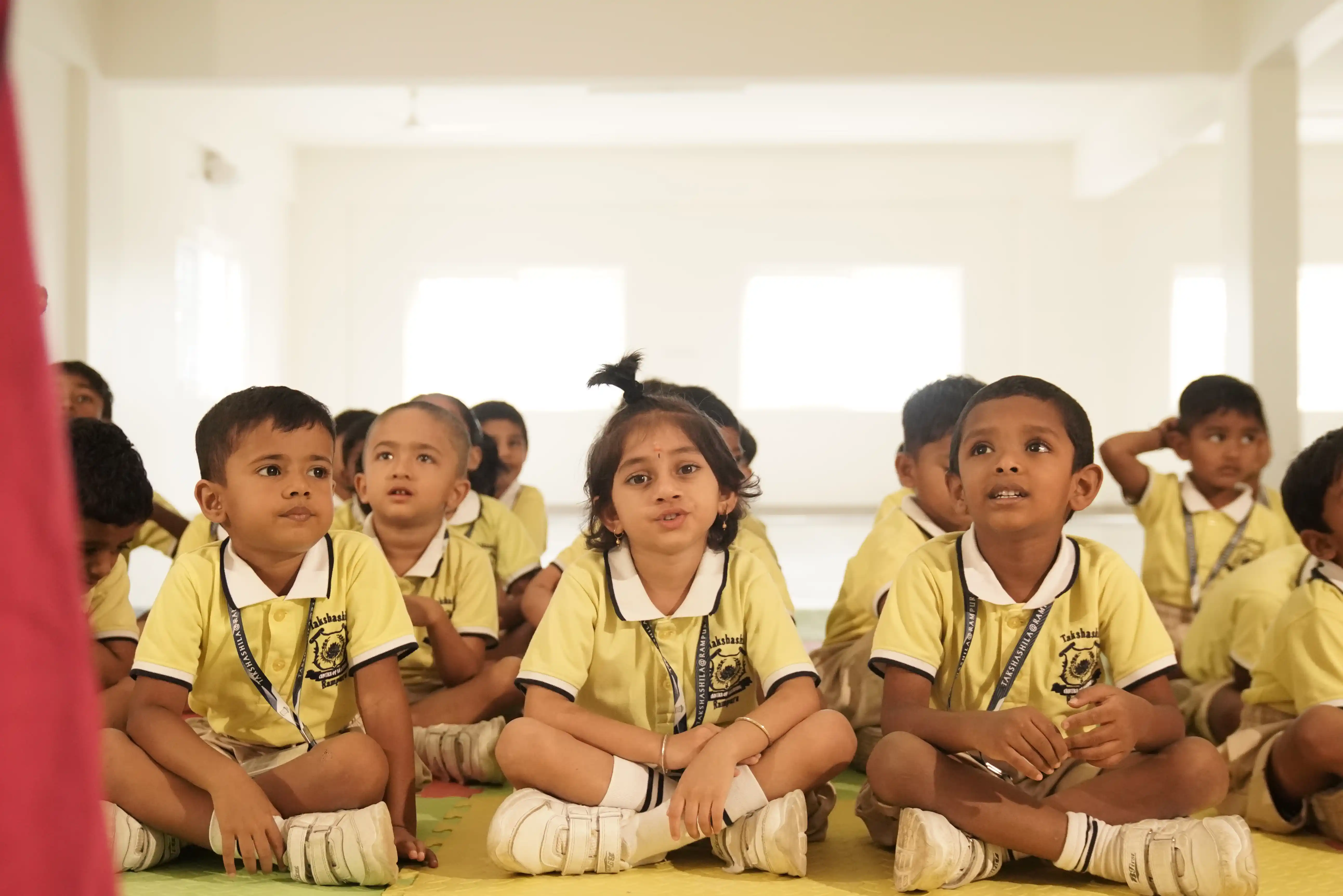 Pre-school children in yellow uniforms sitting together at Takshashila School @ Rampura