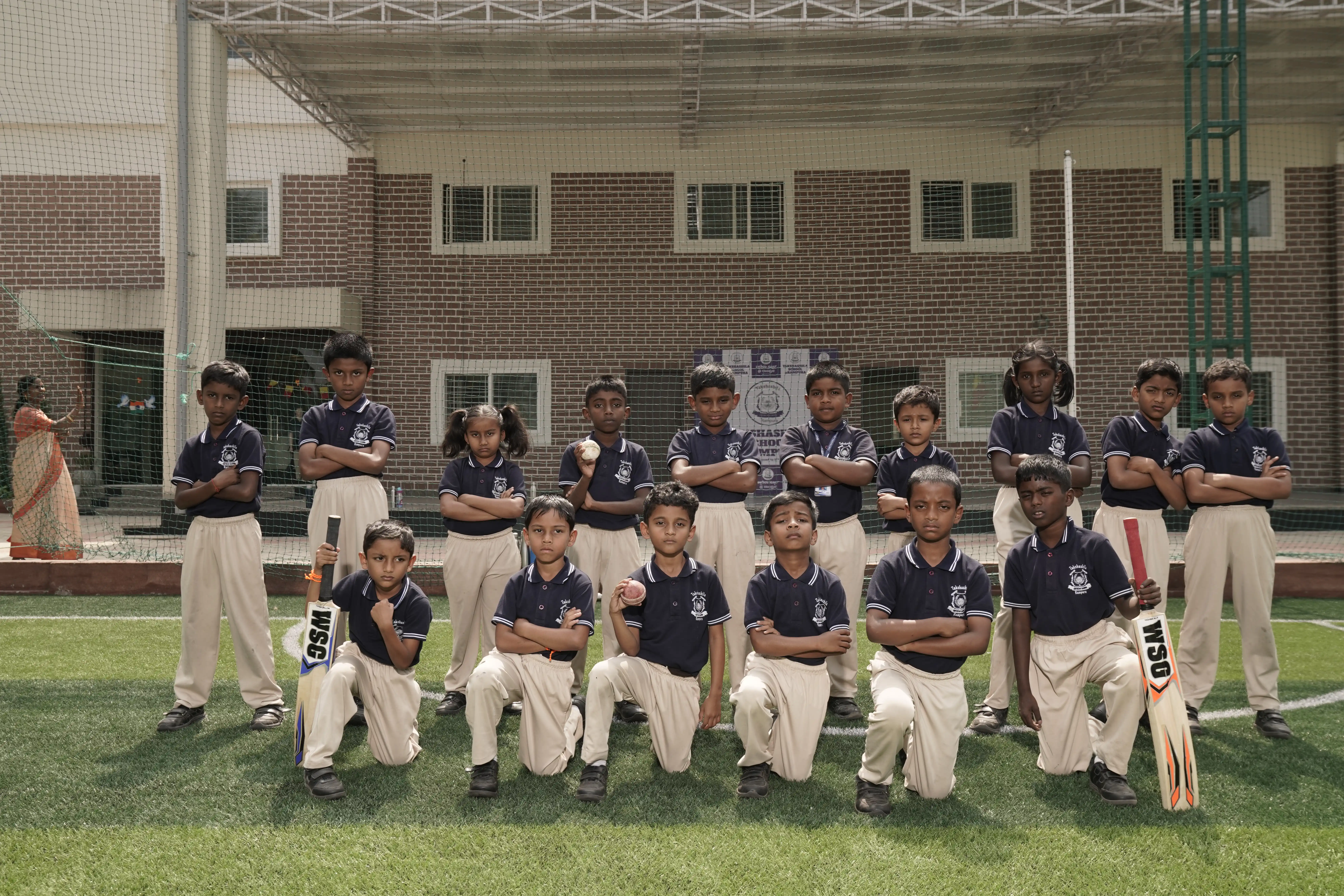 Students in sports kit with cricket bats on the turf at Takshashila School @ Rampura