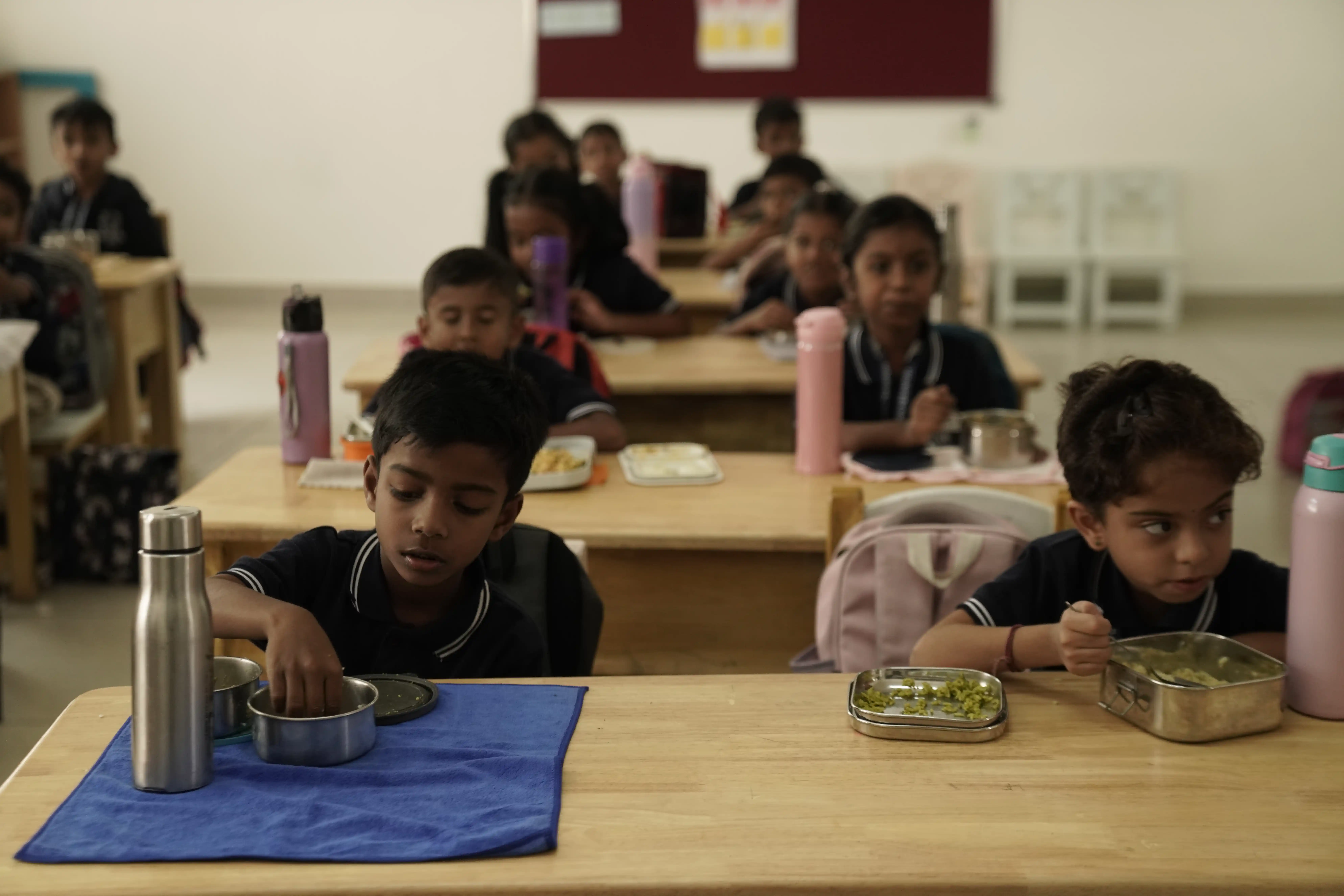 Primary students having lunch at their desks in a Takshashila School classroom