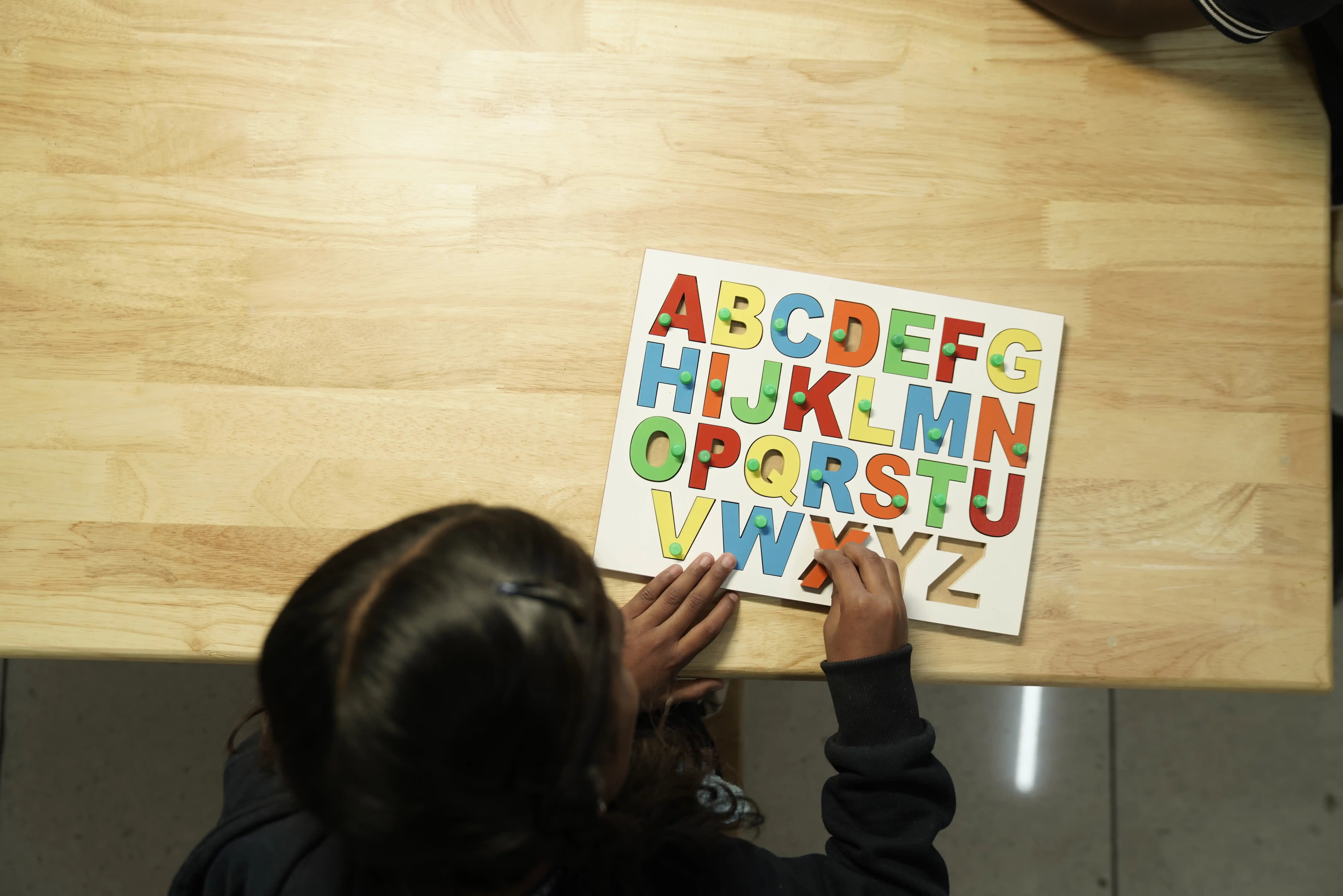 Pre-school child working on an alphabet puzzle at Takshashila School