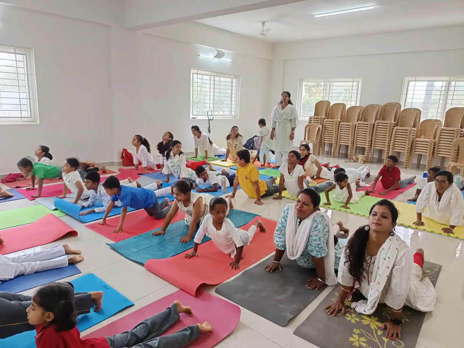 Children practising yoga on mats with their teachers at Takshashila School @ Rampura