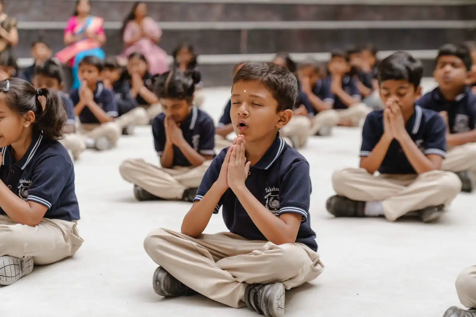 Students meditating with folded hands during a session at Takshashila School